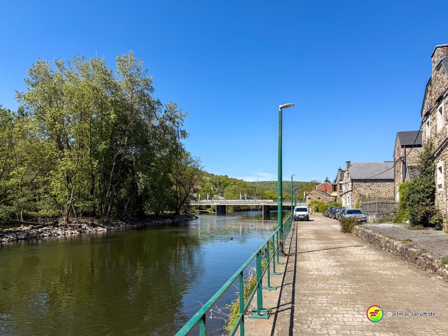 Die Ourthe mit einer Brücke, am Ufer eine schmale Straße mit parkenden Autos.