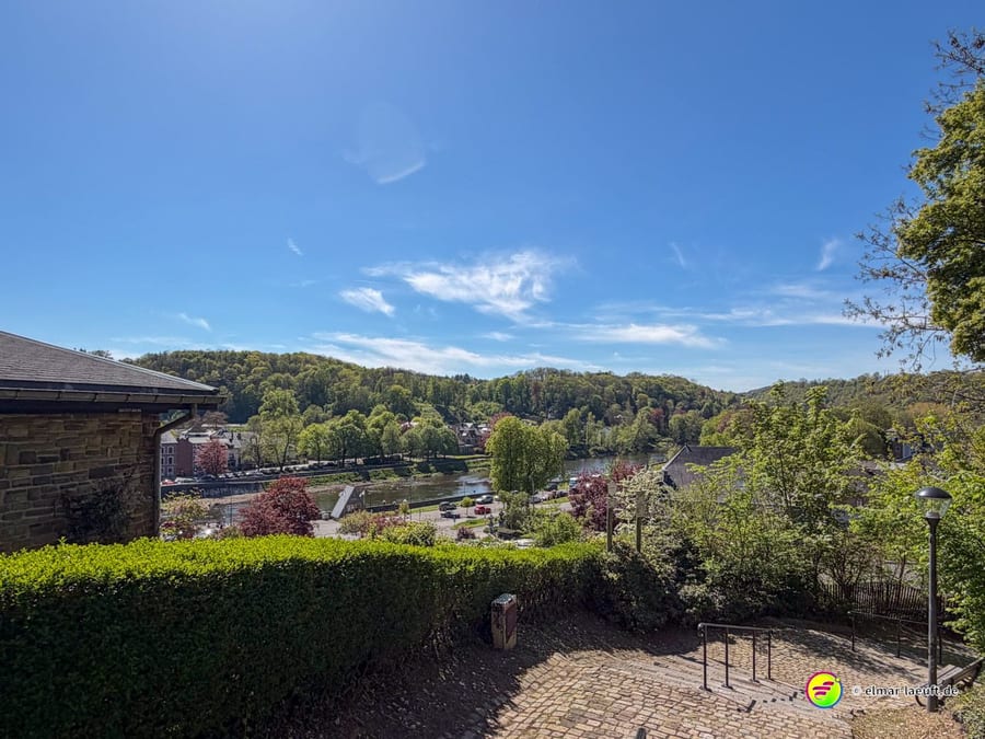 Von einer Terrasse über Hecken hinweg auf das Tal und den Ort darunter.