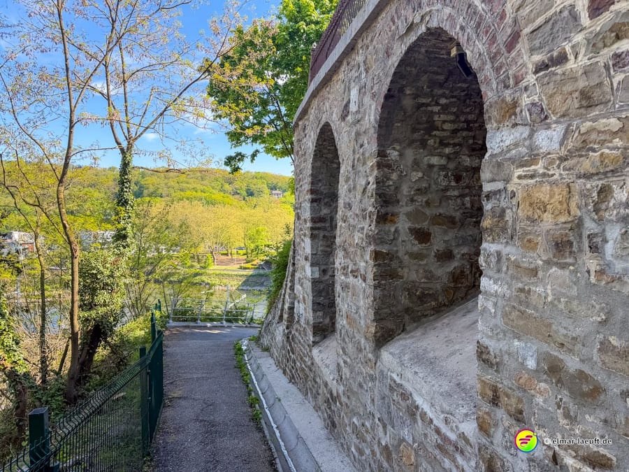 Weg neben einer Bruchsteinmauer mit einer gemauerten Bogennische.