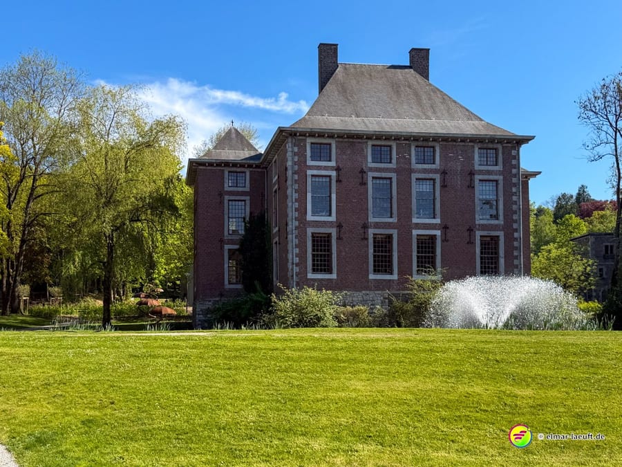 Backsteinherrenhaus mit hohem Dach in einer weiten Parkanlage.