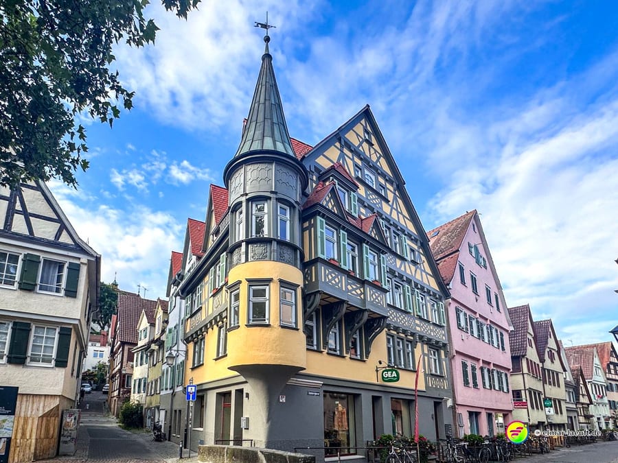 Laufen durch die historische Altstadt von Tübingen mit Fachwerkhäusern und einem markanten Turm bei blauem Himmel.