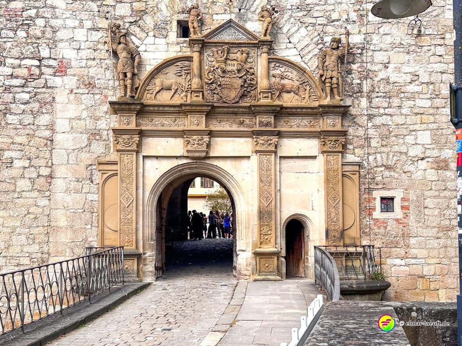 Laufen durch das historische steinerne Stadttor in Tübingen mit einer Gruppe Menschen im Hintergrund an einem klaren Tag.