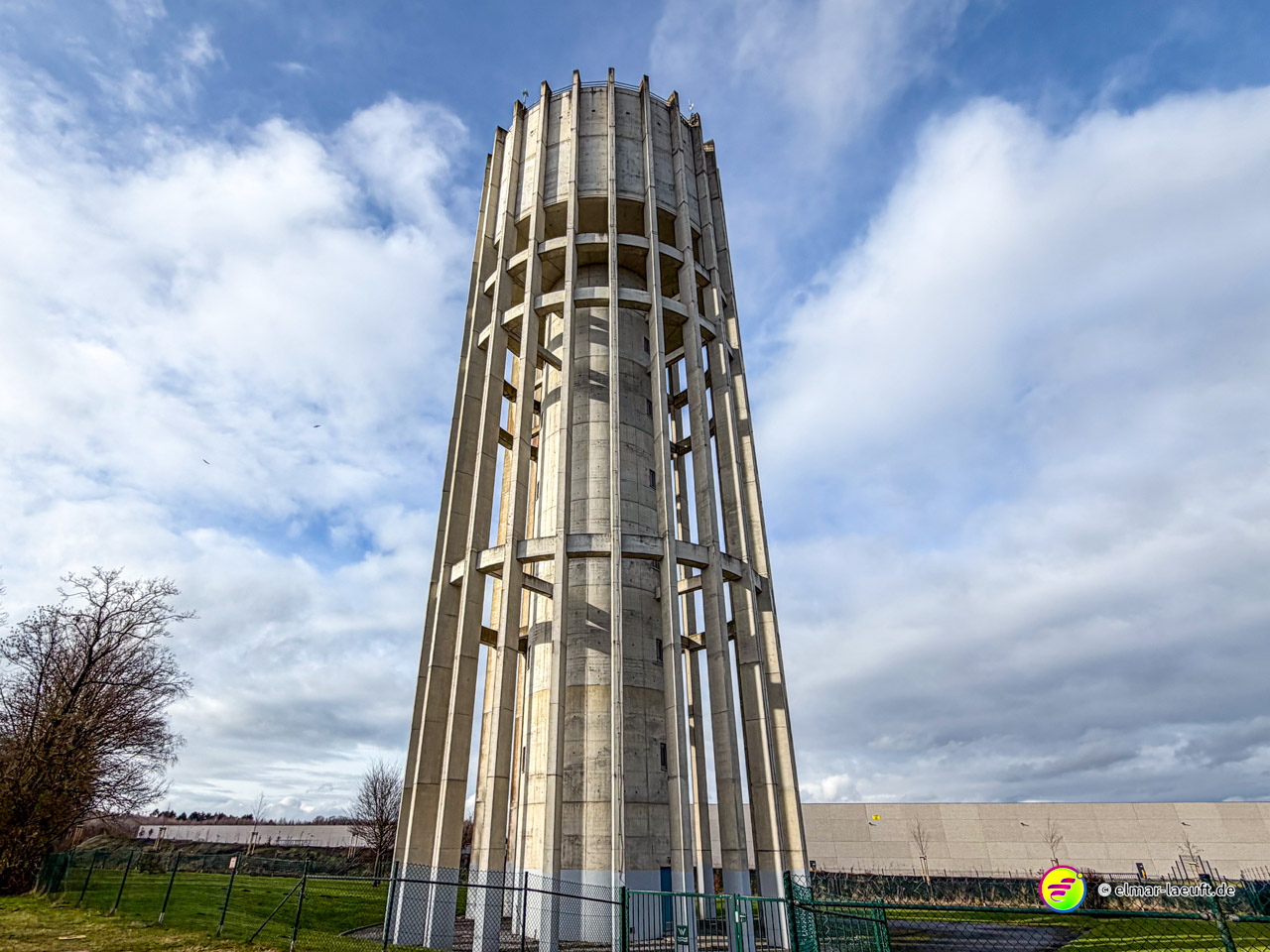 Moderner Wasserturm in skelettartiger Betonarchitektur mit zylindrischem Reservoir. Die offene Konstruktion mit vertikalen Betonstreben zeigt typische Ingenieurbauweise der Nachkriegszeit.