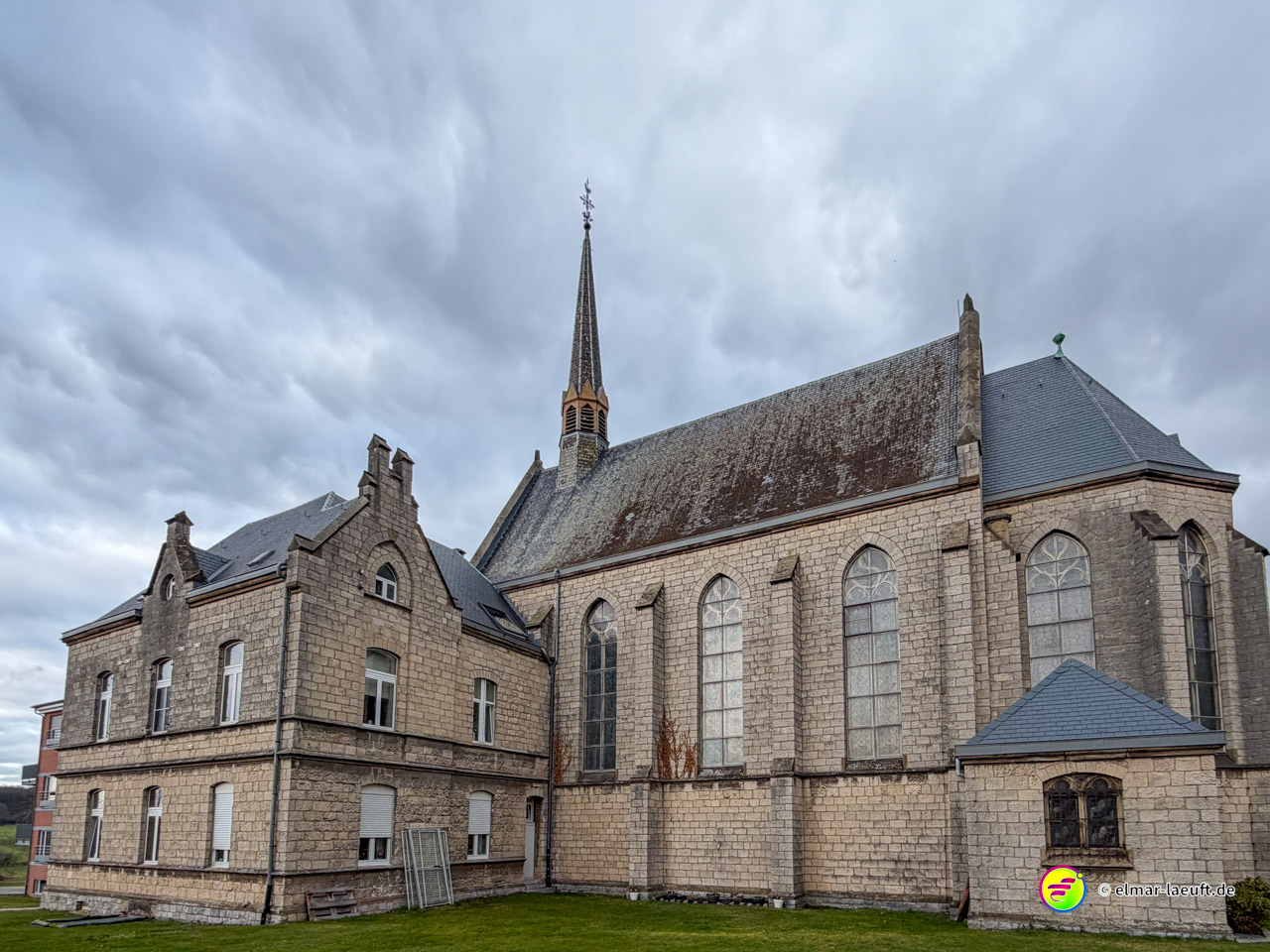 Großes neugotisches Kirchengebäude aus hellem Naturstein mit hohen Spitzbogenfenstern. Die imposante Kirche zeigt typische Merkmale des 19. Jahrhunderts mit Strebepfeilern und Satteldach.