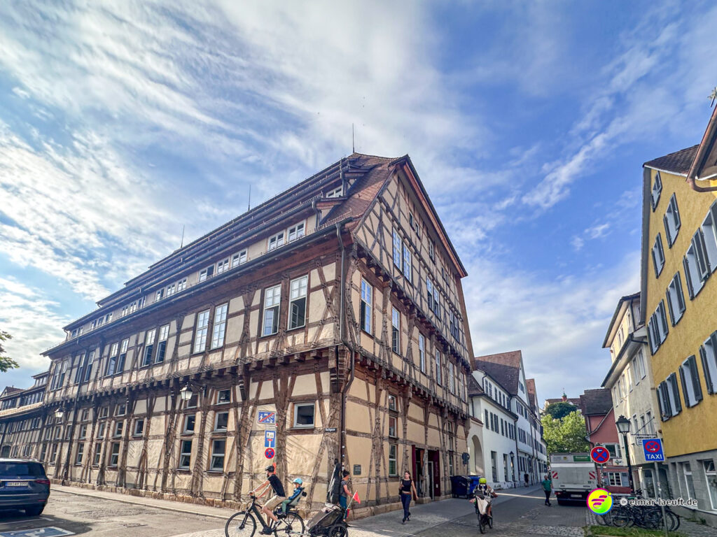 Laufen in Tübingen entlang einer Straße mit historischen Fachwerkhäusern unter einem bewölkten Himmel.
