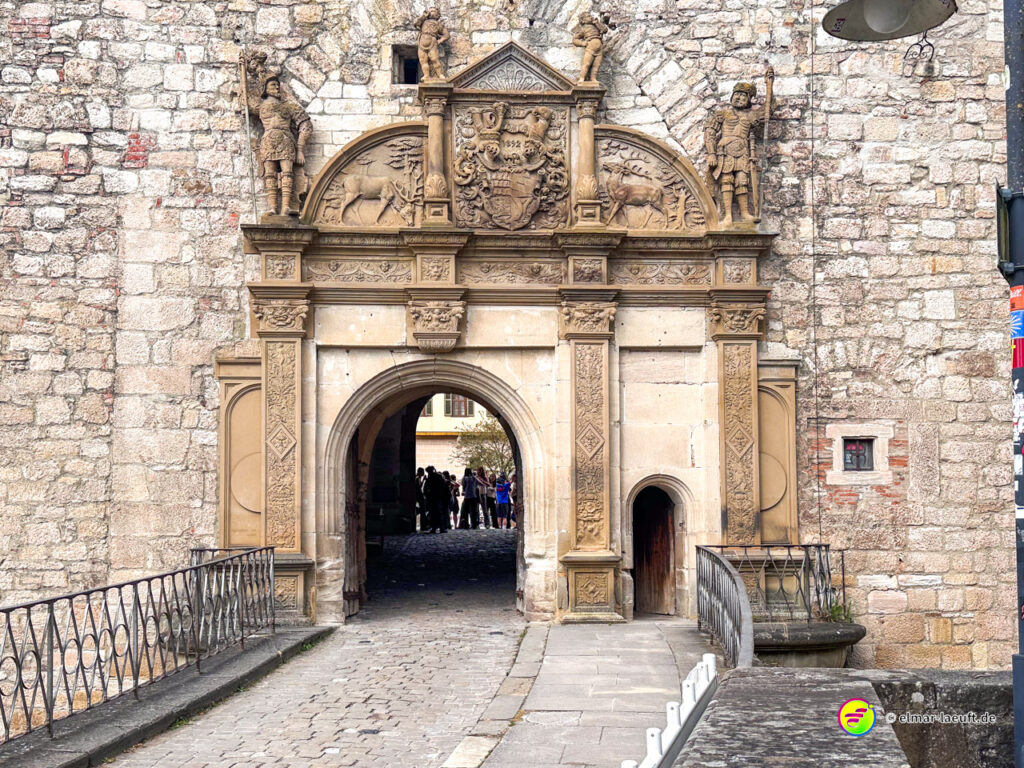 Laufen durch das historische steinerne Stadttor in Tübingen mit einer Gruppe Menschen im Hintergrund an einem klaren Tag.