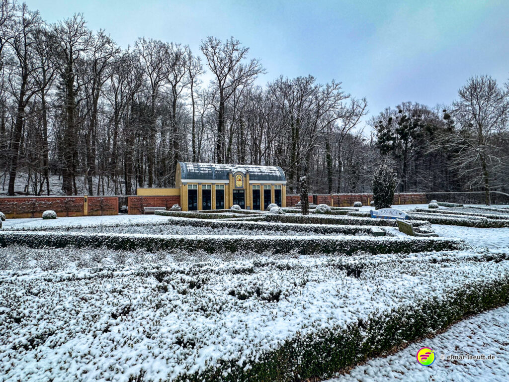 Laufen im winterlichen Park von Heerlen mit verschneiten Hecken und kahlen Bäumen im Hintergrund.