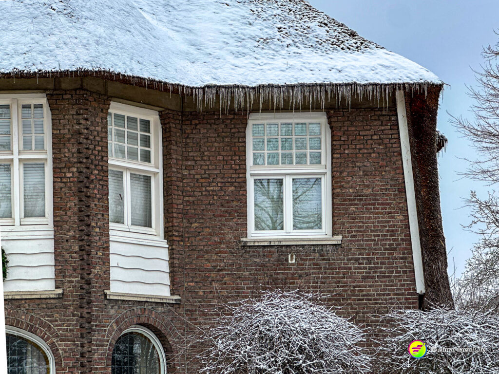 Laufen in Heerlen mit Blick auf ein schneebedecktes Hausdach und Eiszapfen an einem kalten Wintertag.