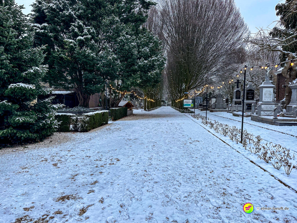 Laufen auf einem schneebedeckten Weg zwischen Bäumen und Gräbern in einem Friedhof bei Heerlen.