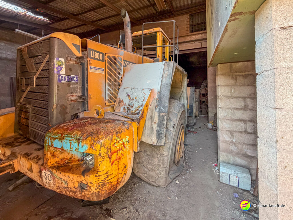 Laufabenteuer in Maasmechelen führt an einem verlassenen, verrosteten Baumaschinen-Giganten in einer alten Halle vorbei.