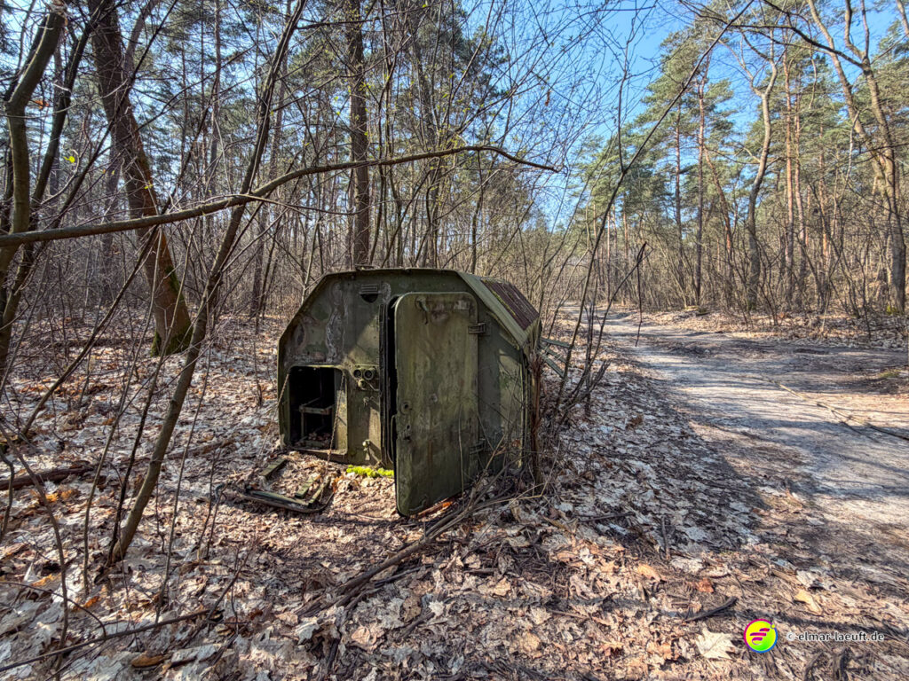 Laufen auf einem schmalen Waldweg in Maasmechelen mit einem verlassenen, verrosteten Metallcontainer am Wegesrand.