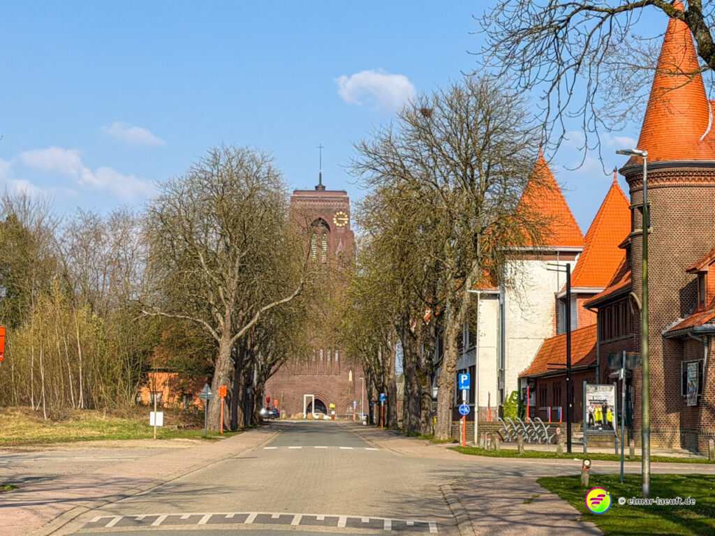 Laufen in Maasmechelen auf einer ruhigen Straße mit Bäumen und markanten roten Dächern im Ortskern.