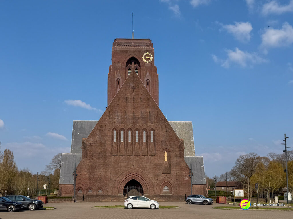 Laufen in Maasmechelen mit Blick auf eine große, markante Backsteinkirche bei klarem Himmel.